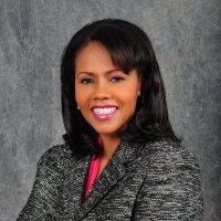 A woman smiles in front of a gray background.
