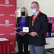 A woman and man with masks on hold awards.