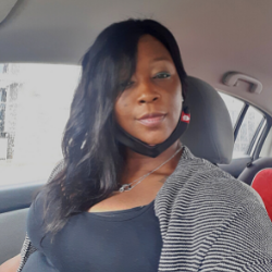 A women sits smiling in her car.