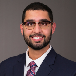 A man in a suit smiles for a photo.