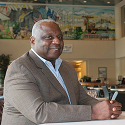 A man in a suit smiles while sitting at a table.