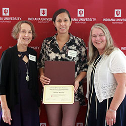 Three woman stand posing for a photo.