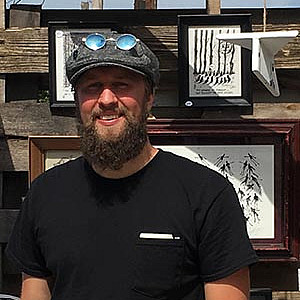 A man stands outdoors smiling in front of art.