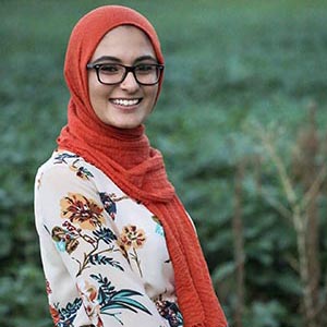 A women stands smiling outside.