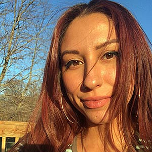 A woman stands outside smiling.