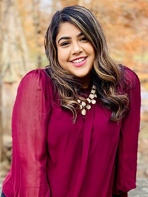 A woman smiles outdoors.