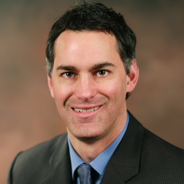 A man in a suit smiles.