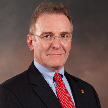 A man in a suit smiles.