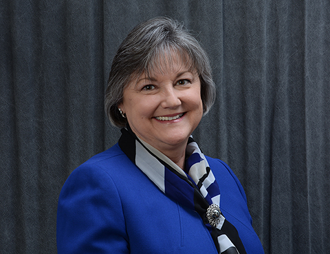 A woman smiles in front of a curtain.