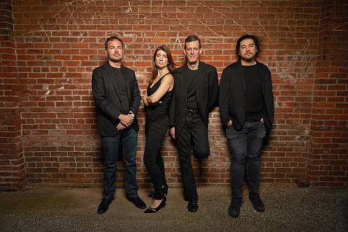 A group of people stand in front of a brick wall.
