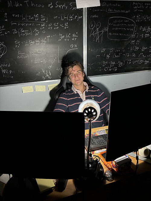 A man sits in front of computers in the dark.