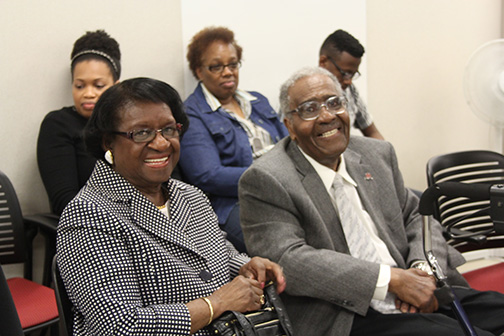 Two people sit smiling during an award ceremony.