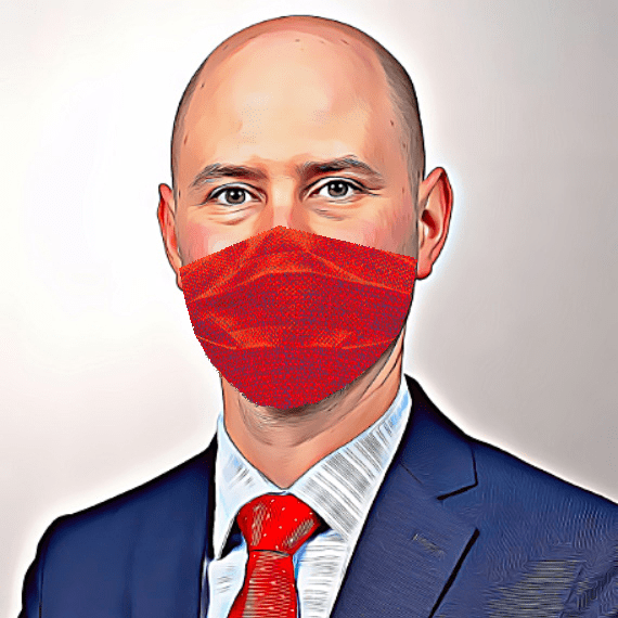 A man wearing a mask poses for a headshot.