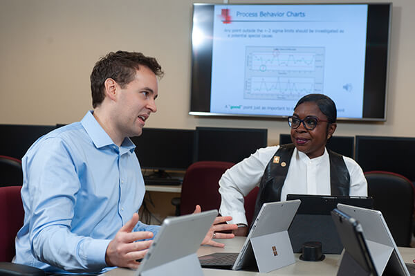 A man and woman talking while working on computers.