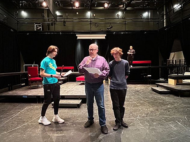 Actors practice a performance in a black box theatre.