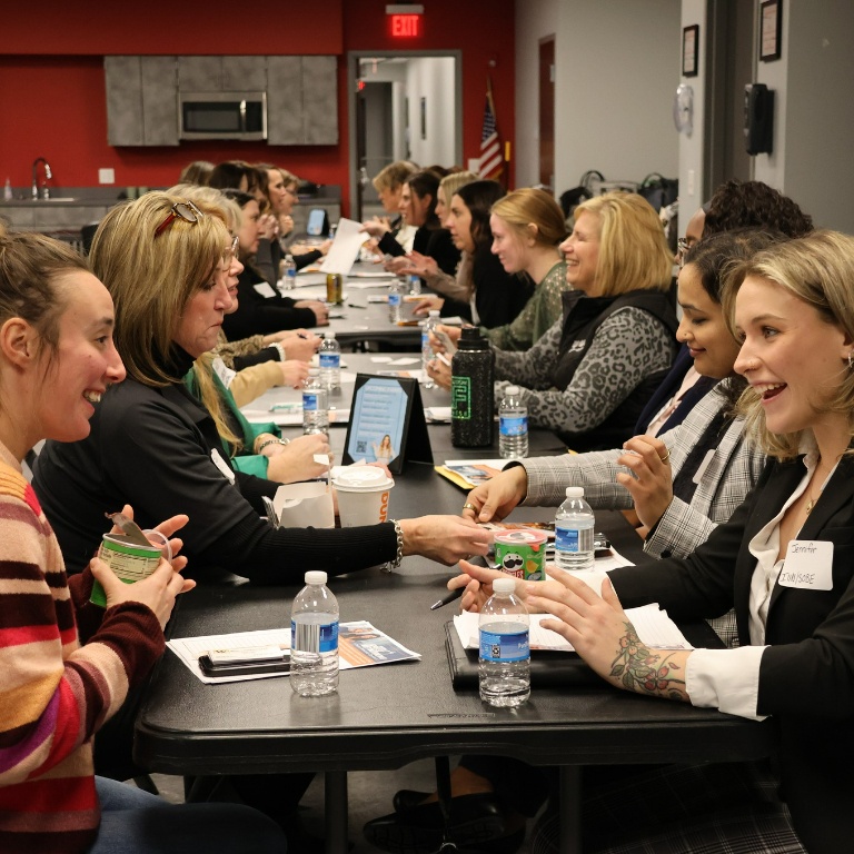 A group of women sit on two sides of a table.