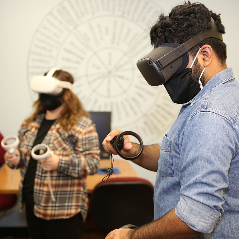 Two students in a classroom wearing virtual reality headsets.
