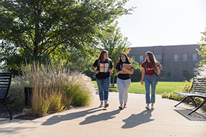IU East students carrying books and backpacks as they walk and talk along the quad
