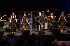 Soul Revue, dressed in black attire performing on stage with a band