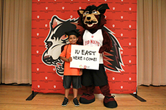 IU East's Rufus the Red Wolf mascot posing with grade school student and holding IU East sign