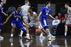 Men's basketball team during a game. One team is in blue jerseys and the other in white.