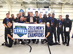 Team dressed in black shirts and pants, holding a banner that says 2020 Men's Indoor Track & Field Champions