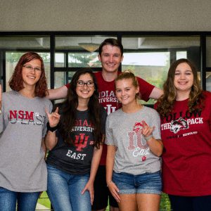 A group of IU East students sporting IU East t-shirts smile and pose