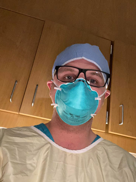 Nurse Keaton Akers wearing a PPE mask and gown over scrubs
