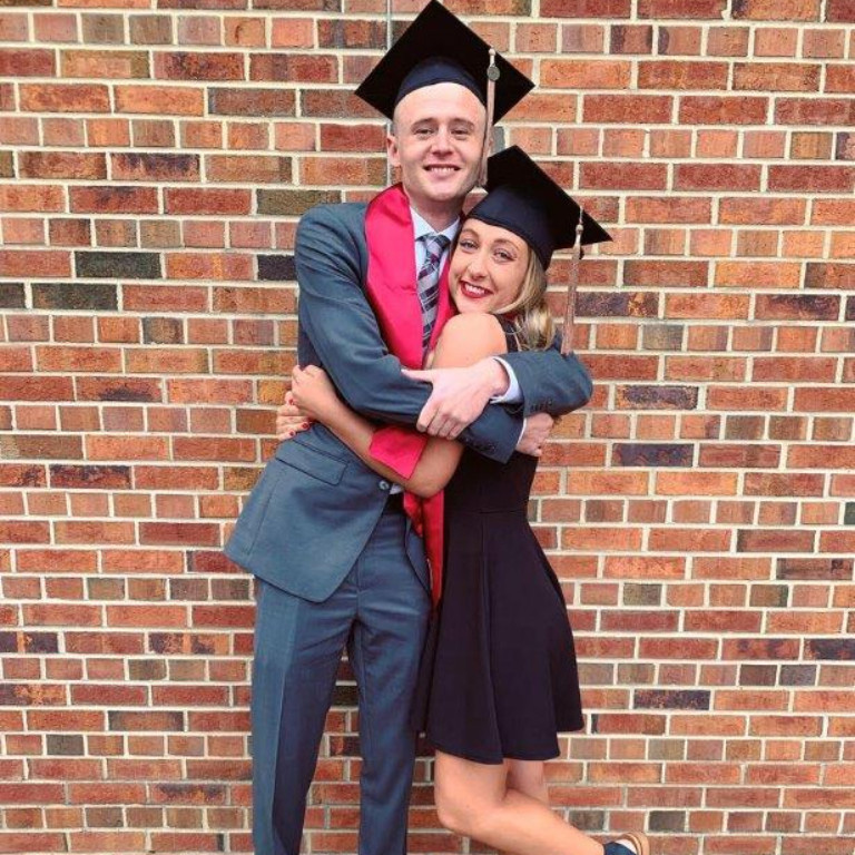 Hunter Wilson and Brooklyn Hubbard hugging each other tightly in their ceremonial mortarboards and stoles