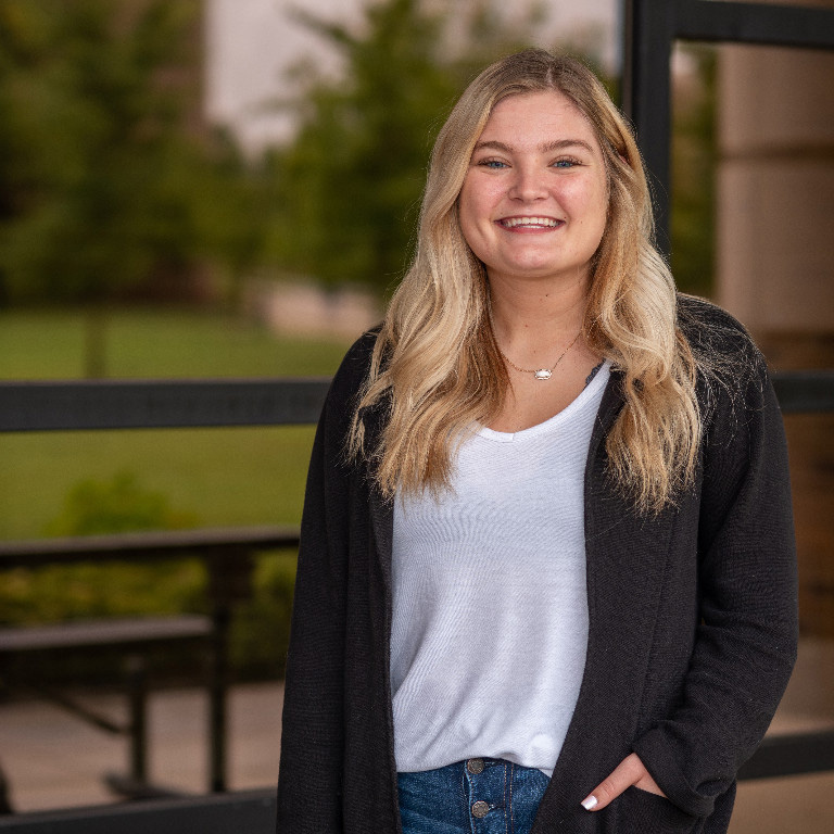 Morgan Weaver smiling, left hand casually in the pocket of her cardigan