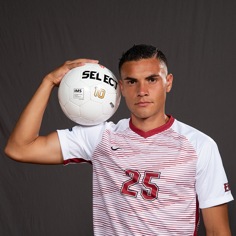Matt Fletes wearing sportswear and holding a soccer ball on his shoulder.