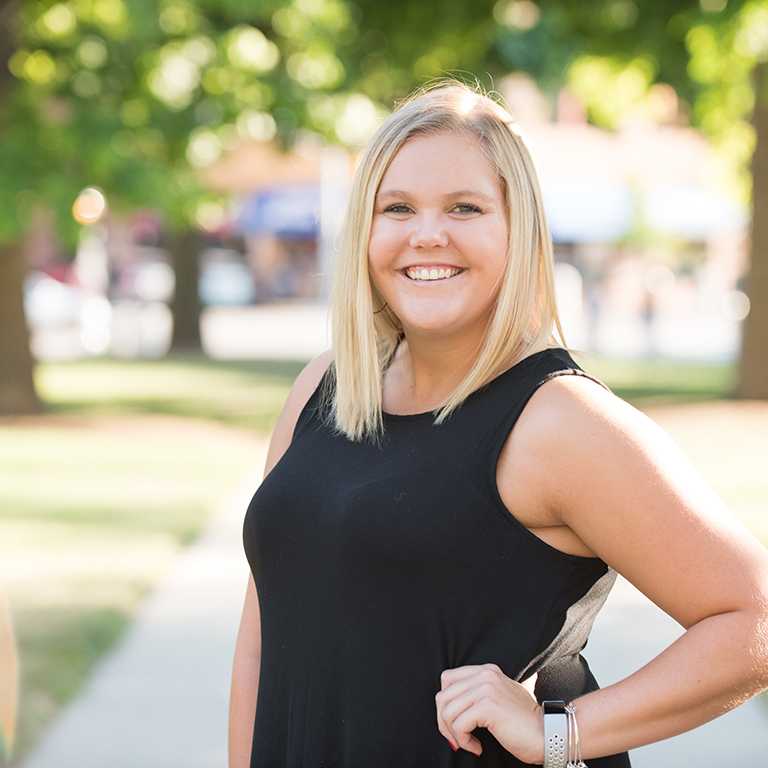 Samantha Elleman, smiling on a sunny day with trees in the background.