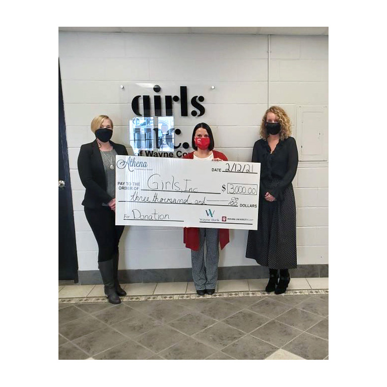 Marcy Crull receiving a large cheque from JoAnn Spurlock and Paula Kay King in front of Girls inc. sign