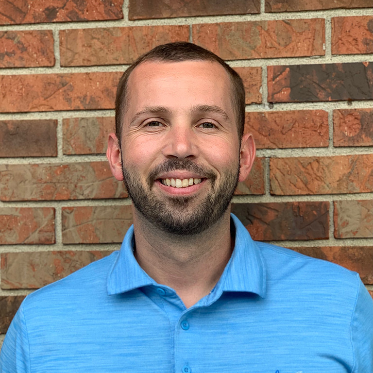Ryan Ashlock smiling in front of a brick wall