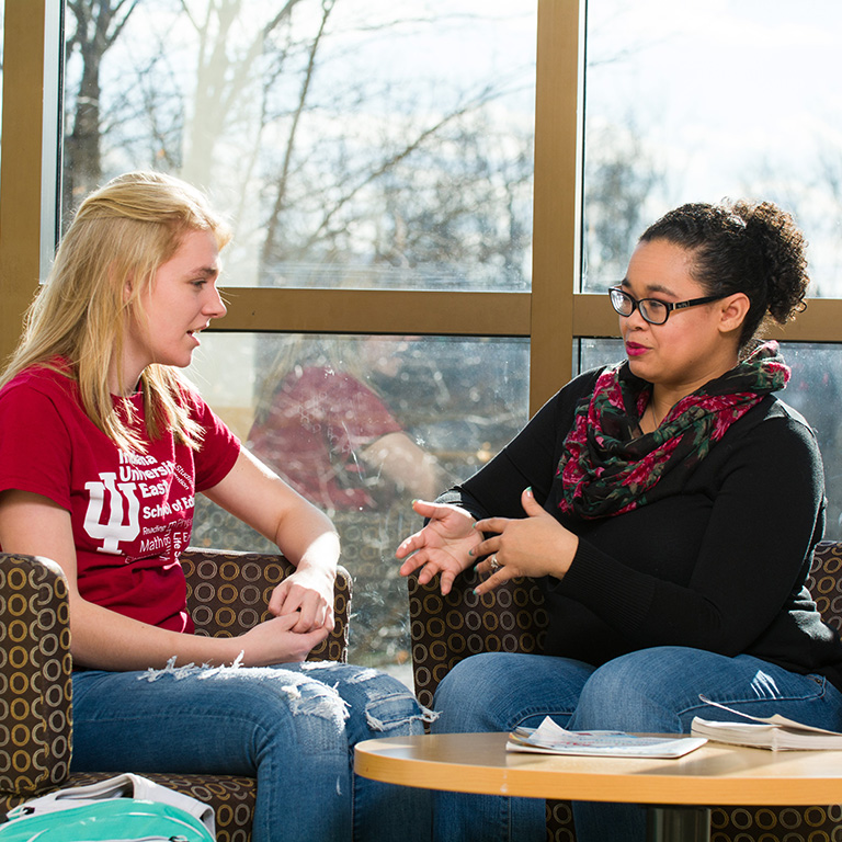 student talking with Nichole Mann at a table and chairs