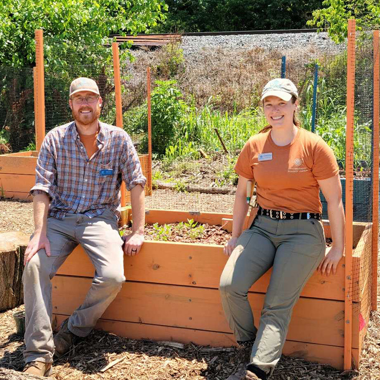 Aaron Comstock sitting on a garden box with Christina Emery