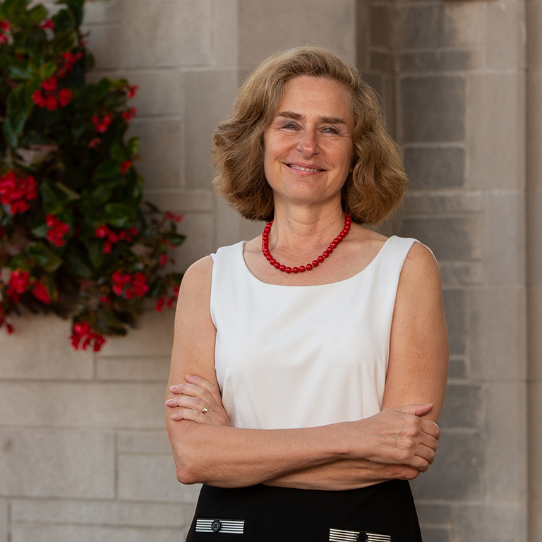 Pamela Whitten standing in front of limestone and flowers