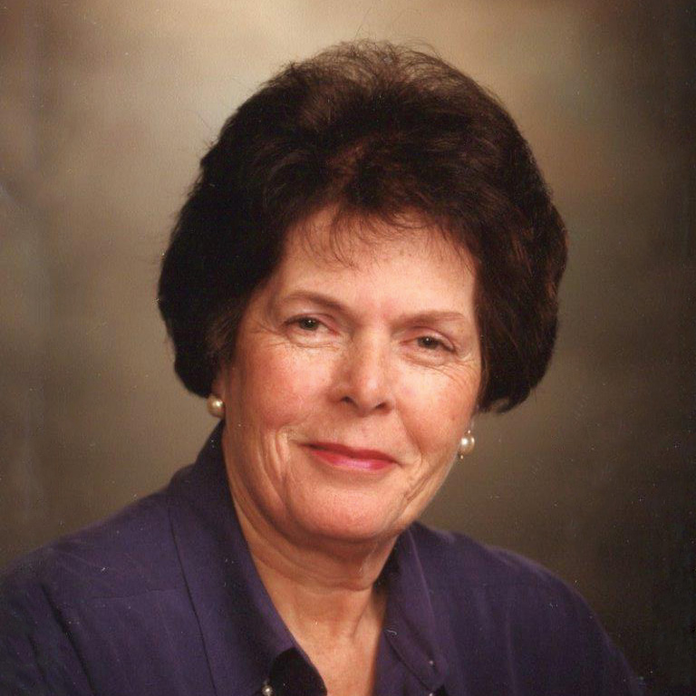 Close-up of Jane Vincent smiling in front of a neutral vignette background