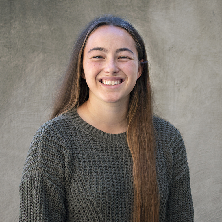 Mackenzie Cook smiling in front of neutral gray background