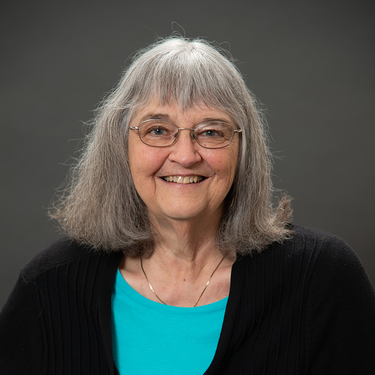 Close-up of Lee Ann Adams smiling in front of dark grey background