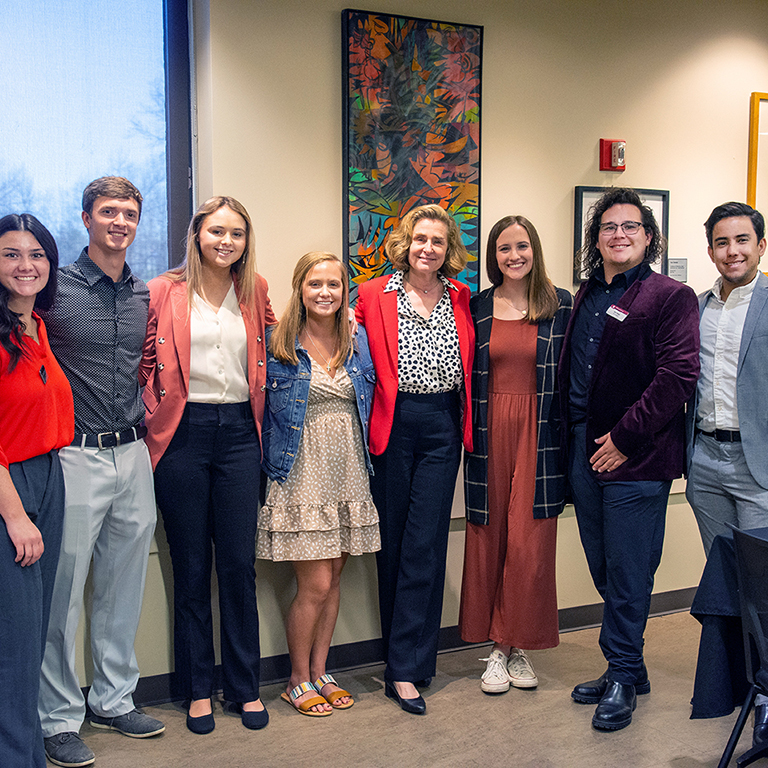 Students meeting with IU President Whitten, standing in the hallway in front of framed artwork