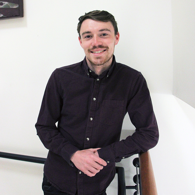 Matthew Paterson smiling, his hands clasped together, resting in front of him