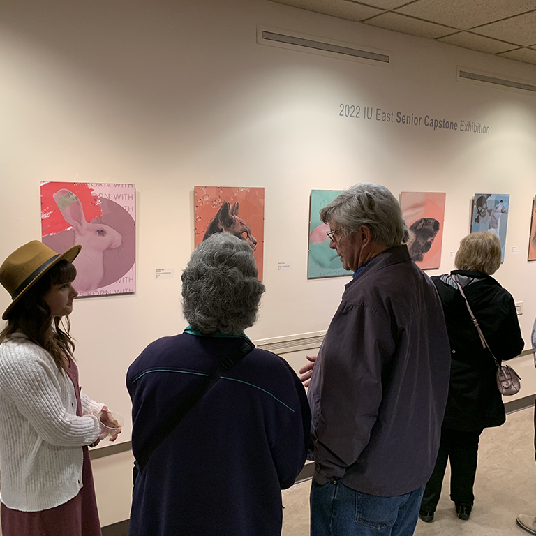 Patrons gathered in front of paintings at the IU East Senior Art Exhibition
