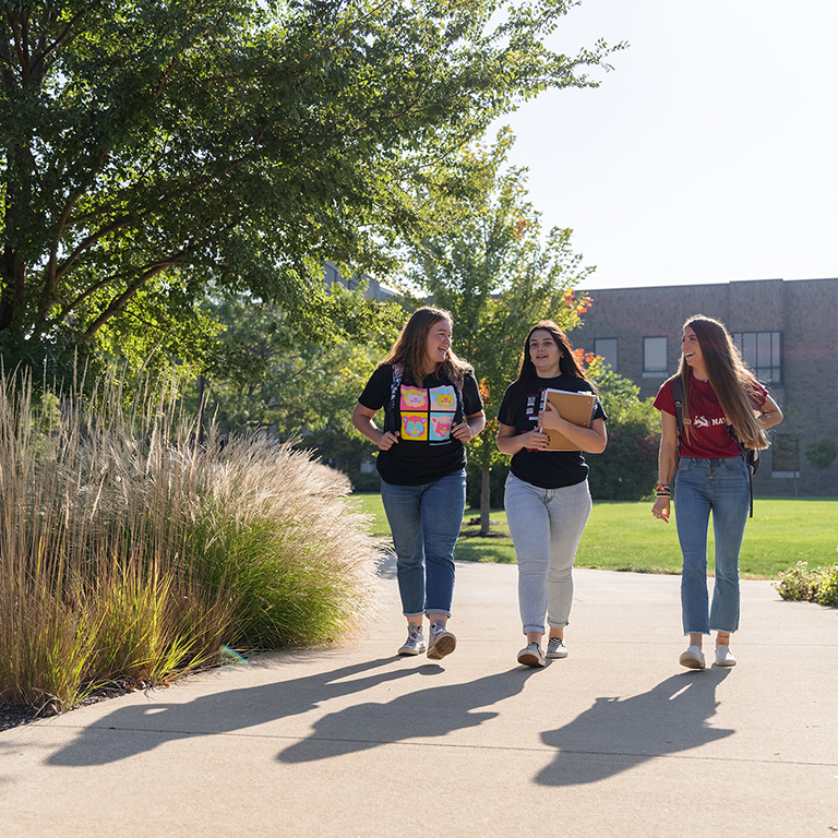 IU East students walk across the quad carrying textbooks and backpacks.