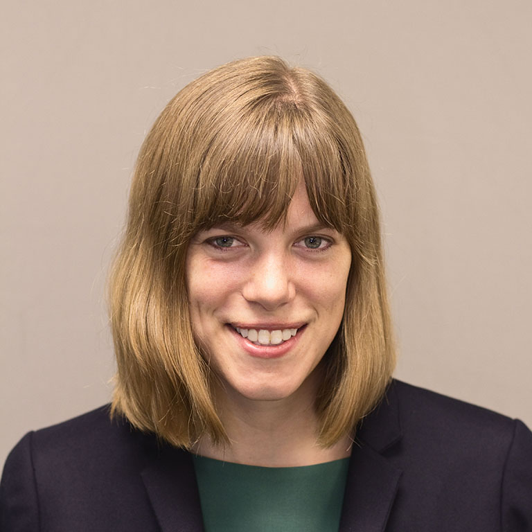 Close-up of Joy Buchanan smiling in front of a neutral tan background