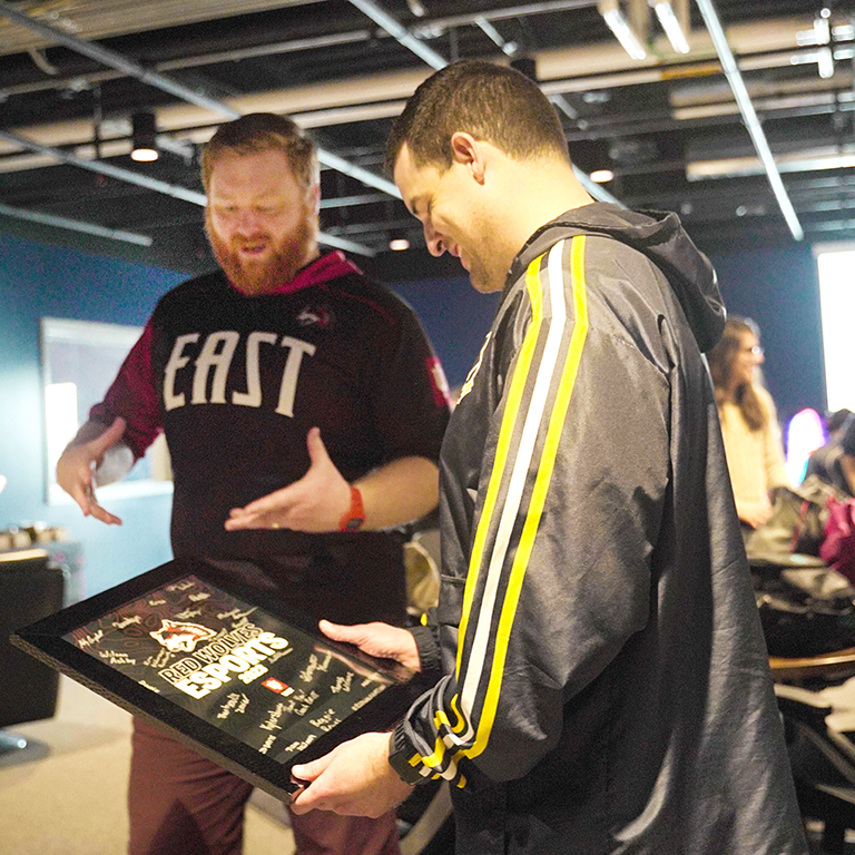 Esports Coach Andrew Britt presents Senior Director of Esports Operations Cody Parrent with Red Wolf signed memorabilia