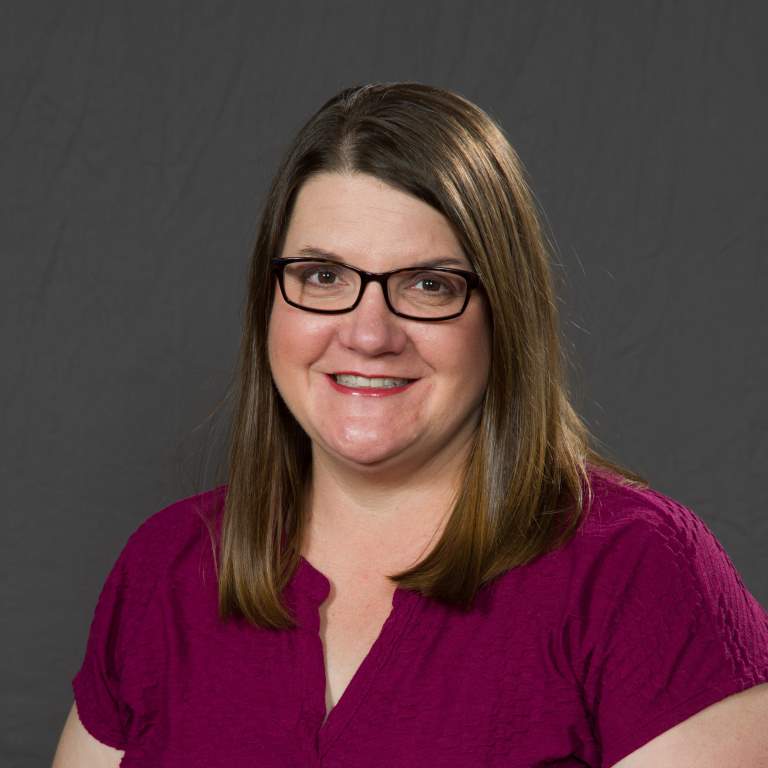 Jill Schweitzer smiling in front of a neutral background.