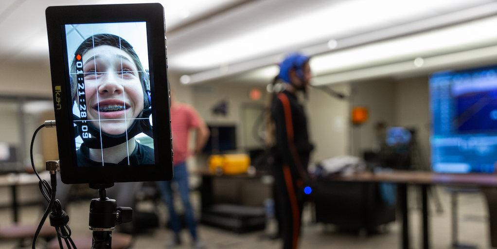 Student wearing motion capture suit and image on screen