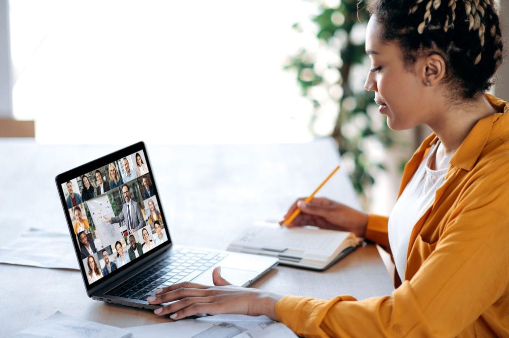A person looks concerned at a laptop screen in a room full of people