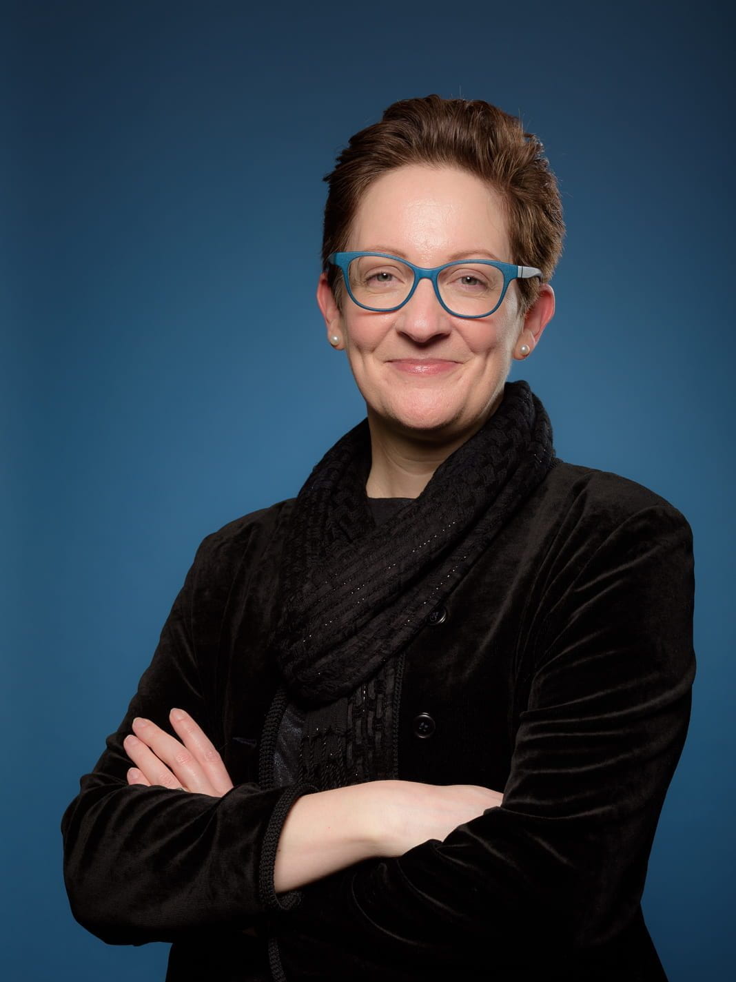 Nine people stand in front of a stone wall.